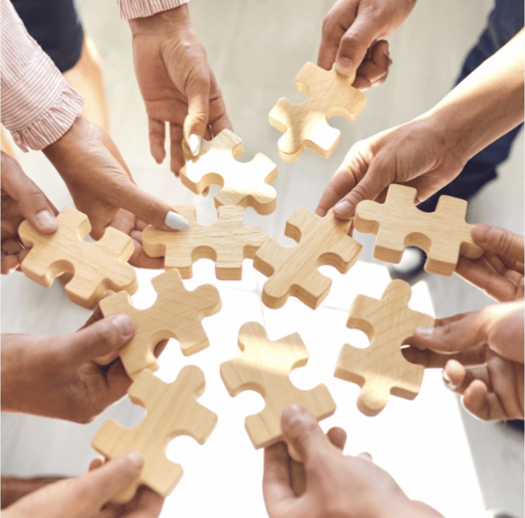 Team members fitting wooden puzzle pieces together