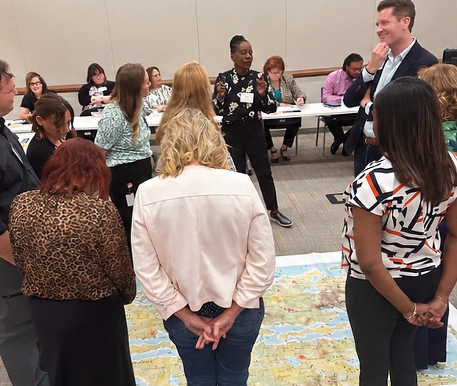 Leaders standing on the MapsTell® behavioral floor map during a facilitated session